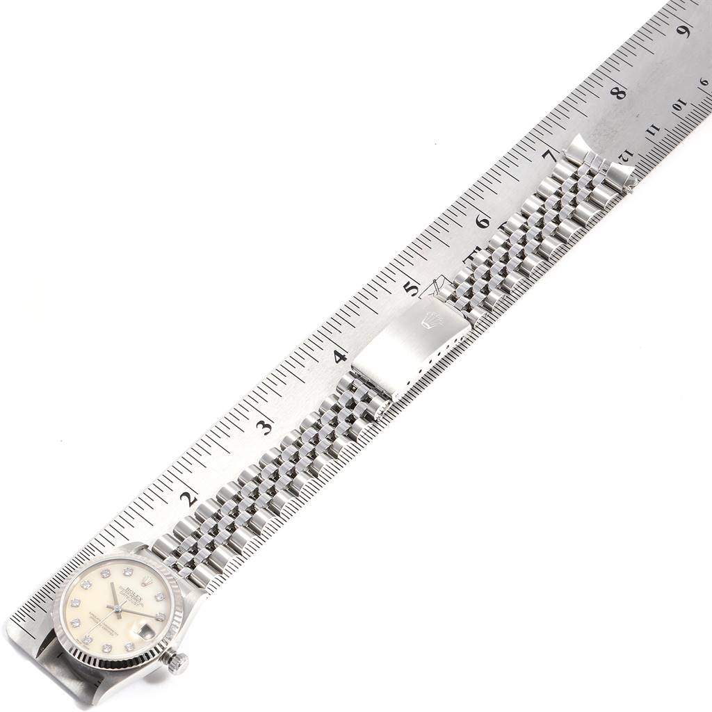 The Rolex Mid-Size 78274 Women's Stainless Steel Mother of Pearl Dial 78274 Women's Stainless Steel Mother of Pearl Dial watch is positioned flat, showing its face, bracelet, and clasp alongside a measuring ruler.