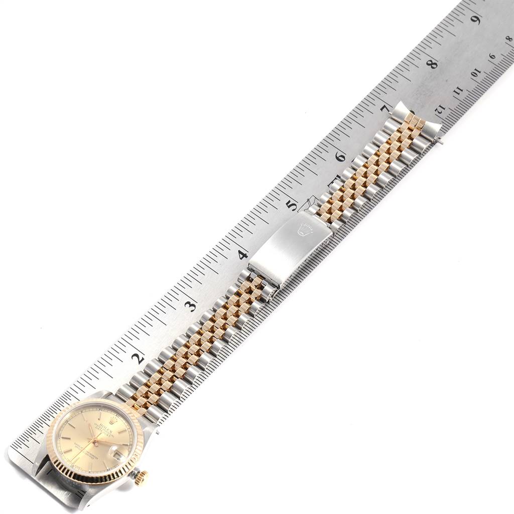 The Rolex Mid-Size 68273 Women's Steel and Gold (two tone) Champagne Dial 68273 Women's Steel and Gold (two tone) Champagne Dial watch is shown from a top-down angle, featuring its face, bezel, bracelet, and clasp next to a ruler for scale.