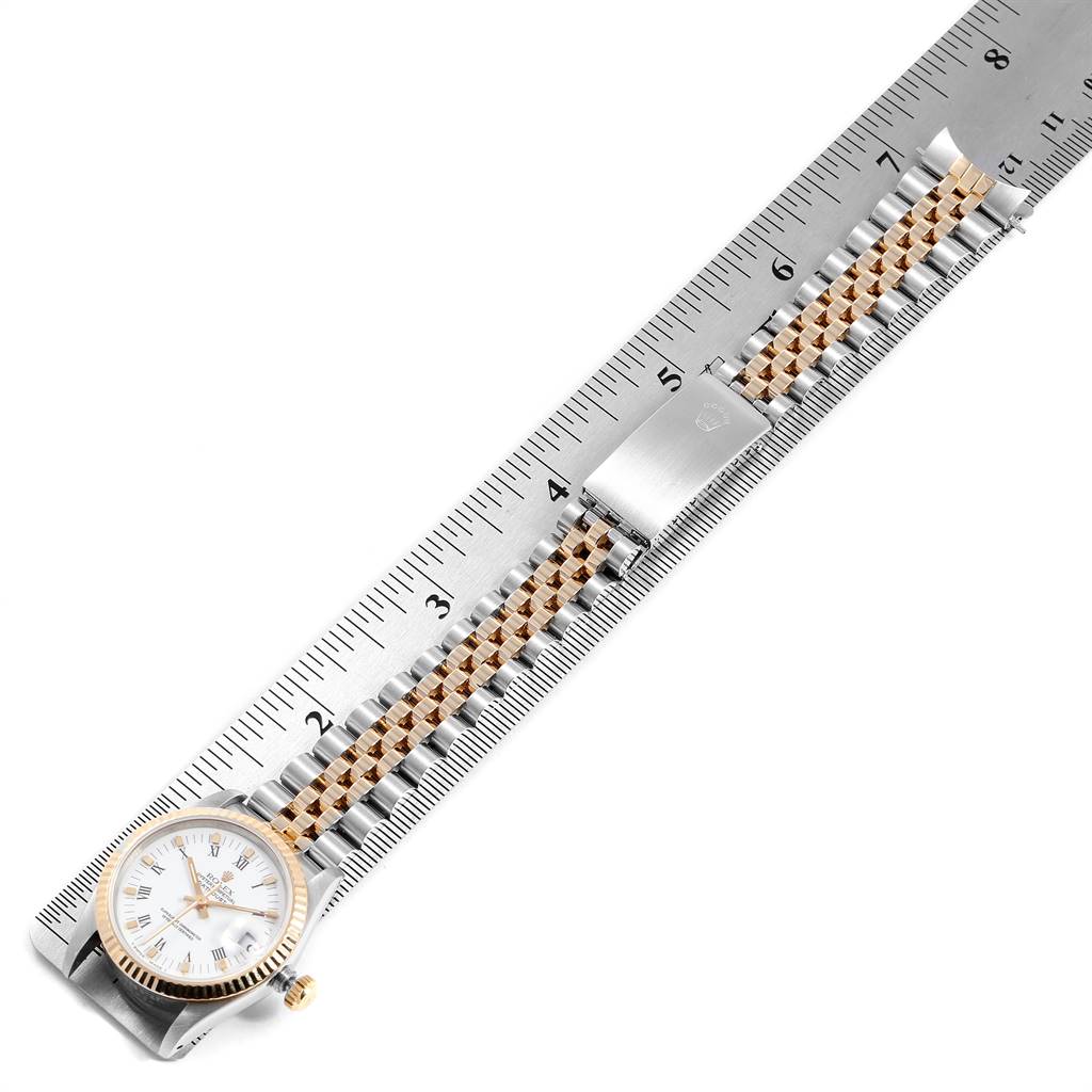 The Rolex Mid-Size 68273 Women's Steel and Gold (two tone) White Dial 68273 Women's Steel and Gold (two tone) White Dial watch is shown flat with its stainless steel and gold bracelet extended alongside a ruler.