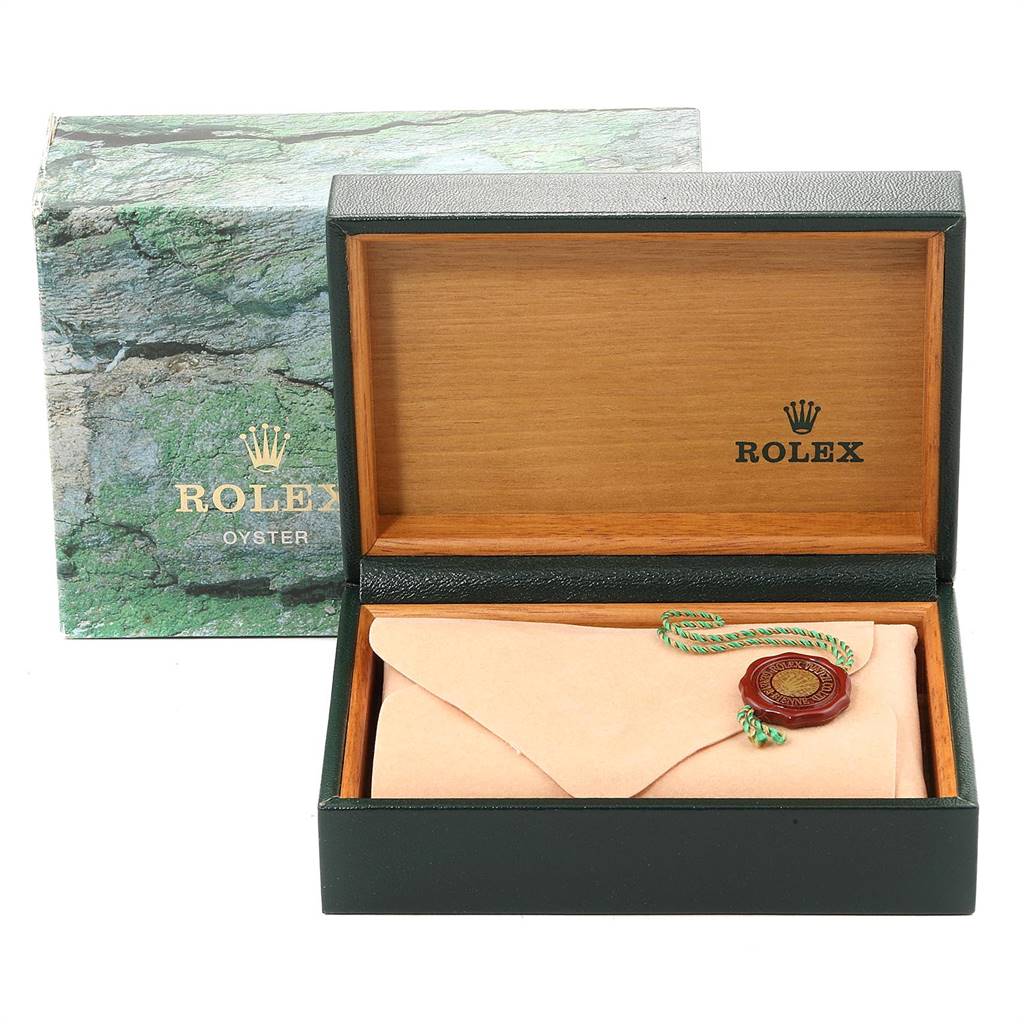 The image shows an open Rolex watch box, a green-brown case, with a Rolex Oyster and the watch's warranty card and seal inside.