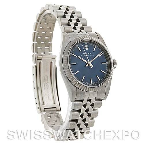 The image shows a Rolex Mid-Size 77014 Women's Stainless Steel Blue Dial 77014 Women's Stainless Steel Blue Dial model watch angled to display the face, crown, and the bracelet's clasp.