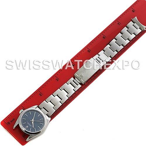 The image shows a Mid-Size Rolex watch laid flat on a red ruler, displaying its face, bracelet, and clasp in a top-down view.