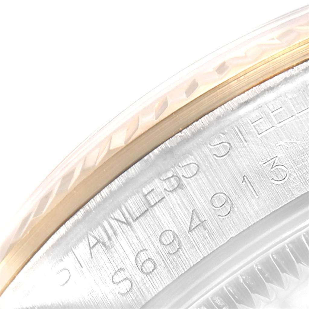 This close-up image shows the engraved serial number and part of the bezel of a Mid-Size Rolex watch.