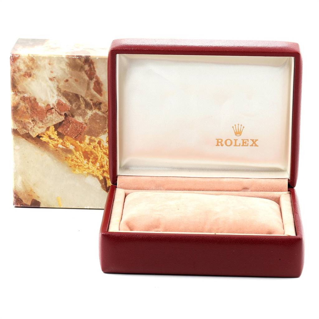 The image shows an open Rolex watch box, with a beige cushion inside and the model's branded exterior packaging visible behind.