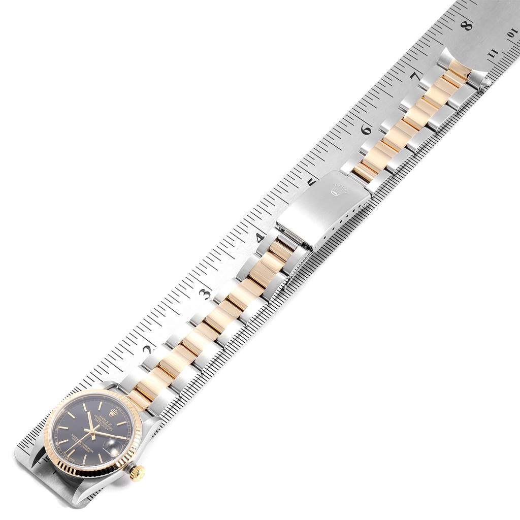 The Rolex Mid-Size 78273 Women's Steel and Gold (two tone) Black Dial 78273 Women's Steel and Gold (two tone) Black Dial model watch is shown from a top view, displaying the face, bracelet, and clasp on a ruler for size reference.