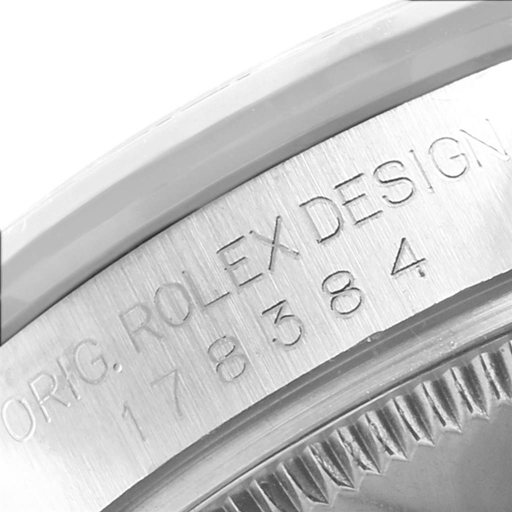 This close-up image shows the side of a Rolex Mid-Size 178384 Women's Stainless Steel Blue Dial 178384 Women's Stainless Steel Blue Dial watch case with the engraved model number 178384 and "ORIG. ROLEX DESIGN."