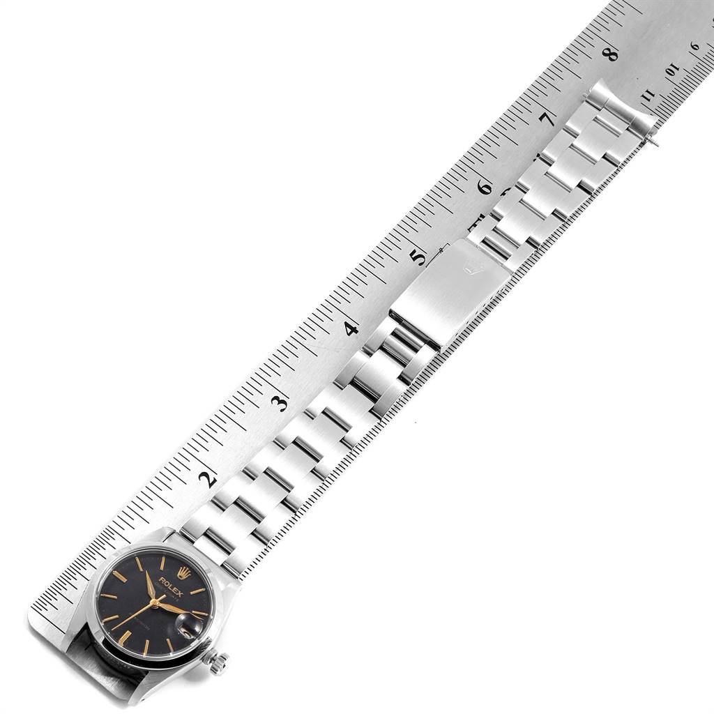 The image shows a Rolex Mid-Size 6466 Women's Stainless Steel Black Dial 6466 Women's Stainless Steel Black Dial model watch at an overhead angle, highlighting the face, band, and clasp on a ruler.