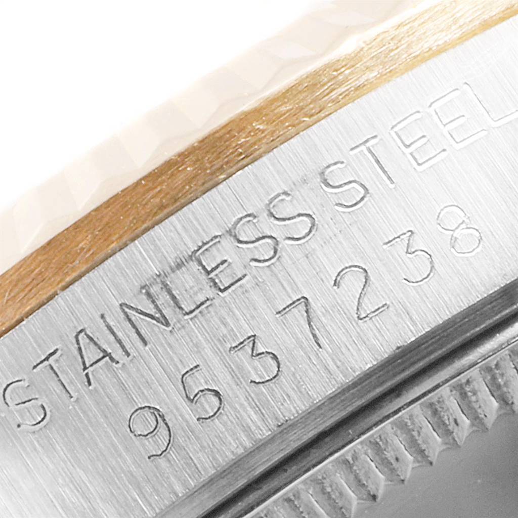 The image shows an angled close-up of the side of a Mid-Size Rolex watch, featuring the serial number and "Stainless Steel" engraving.