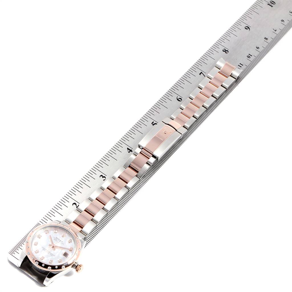 This image shows a Rolex Mid-Size 178341 Women
s Steel and Gold (two tone) Mother of Pearl Dial 178341 Women
s Steel and Gold (two tone) Mother of Pearl Dial watch lying flat beside a ruler, highlighting its clasp and bracelet.