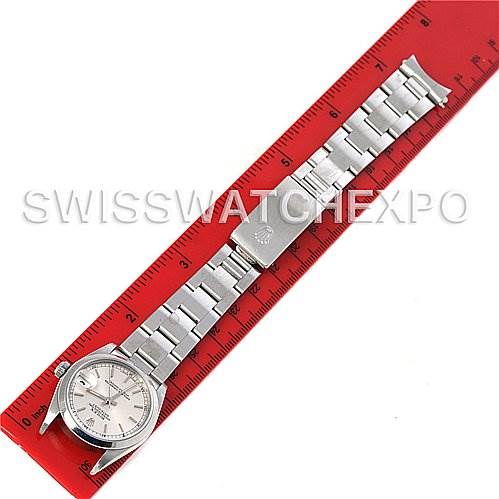 The image shows a top-down view of a mid-size Rolex watch placed alongside a red ruler.