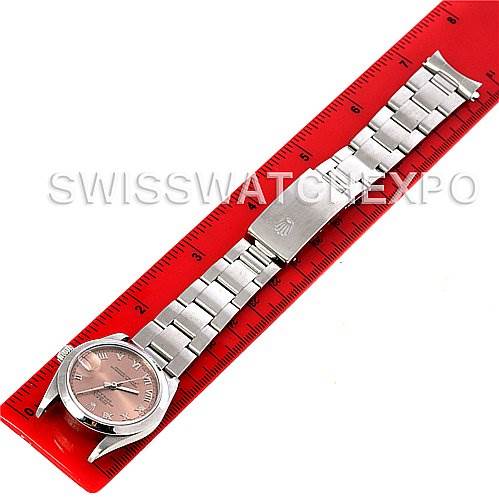 The image shows a top-down view of a Rolex Mid-Size 68240 Women's Stainless Steel Pink Dial 68240 Women's Stainless Steel Pink Dial watch placed next to a red ruler, highlighting its face, bracelet, and clasp.