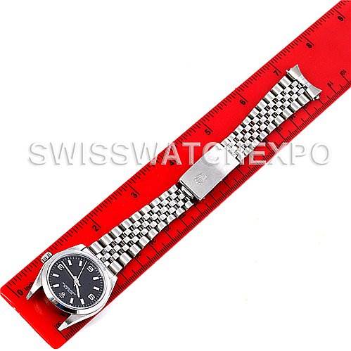 The Rolex Mid-Size 77080 Women's Stainless Steel Black Dial 77080 Women's Stainless Steel Black Dial watch is shown laid flat next to a red ruler, displaying its bracelet and dial.