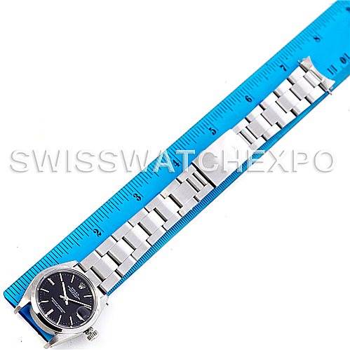 The image shows the front view of a Rolex Mid-Size 6824 Women's Stainless Steel Black Dial 6824 Women's Stainless Steel Black Dial model watch next to a blue ruler, highlighting the watch case and bracelet.