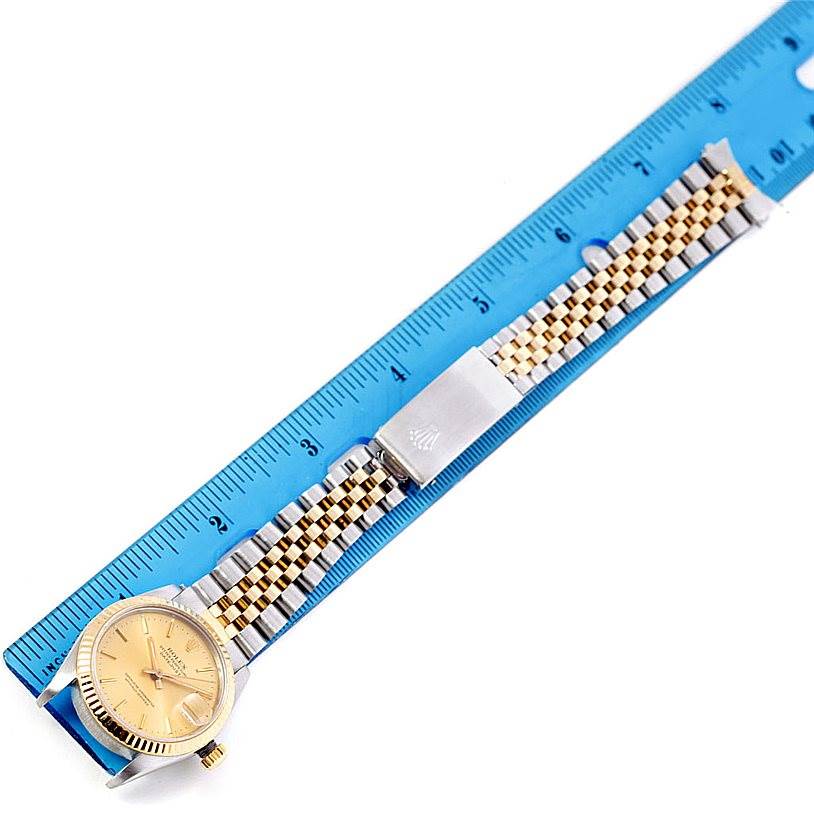 The image shows a Rolex Mid-Size 68273 Women's Stainless Steel Champagne Dial 68273 Women's Stainless Steel Champagne Dial watch laid flat next to a ruler, highlighting its golden dial and two-tone bracelet.