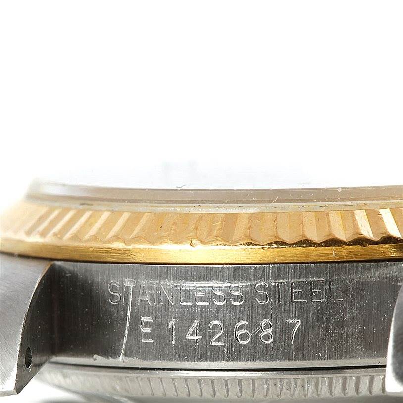 The image shows a close-up of the stainless steel and gold bezel on a Mid-Size Rolex watch, including part of the serial number.