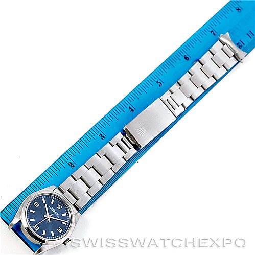 The image shows a Mid-Size Rolex watch laying flat with its steel bracelet fully extended next to a blue ruler for scale.