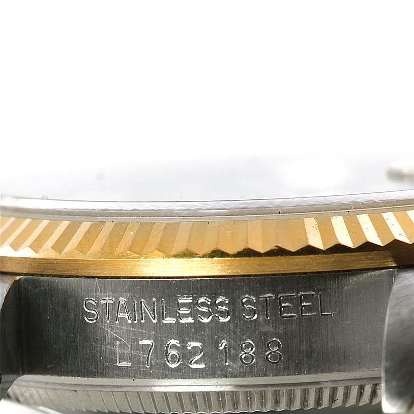 The image shows a close-up of the side of a Rolex Mid-Size 68273 Women's Stainless Steel Blue Dial 68273 Women's Stainless Steel Blue Dial model, highlighting the stainless steel case and the fluted gold bezel.