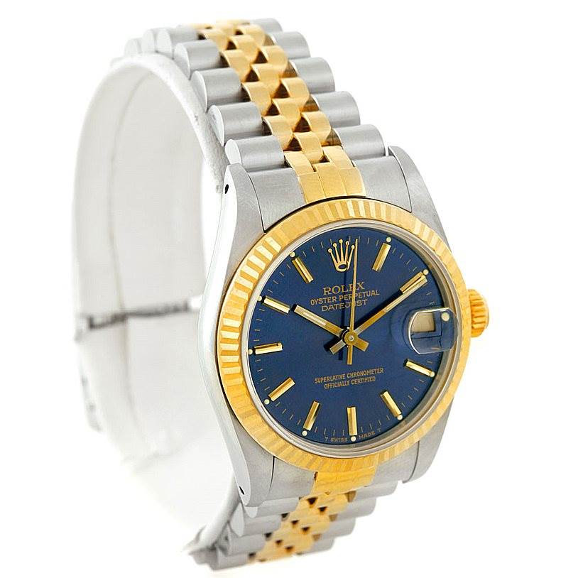 The image shows a Mid-Size Rolex Datejust watch at a slight angle, highlighting its blue dial, gold fluted bezel, and two-tone bracelet.