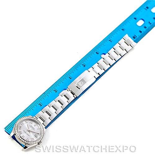 The image shows a top-down view of a Rolex Mid-Size 178384 Women's Stainless Steel Grey Dial 178384 Women's Stainless Steel Grey Dial watch next to a blue ruler, displaying the watch face, band, and clasp.