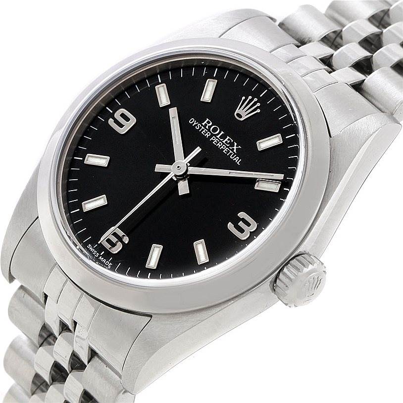 The image shows a Rolex Mid-Size 77080 Women's Stainless Steel Black Dial 77080 Women's Stainless Steel Black Dial Oyster Perpetual watch angled slightly from above, highlighting its face, crown, and part of the bracelet.