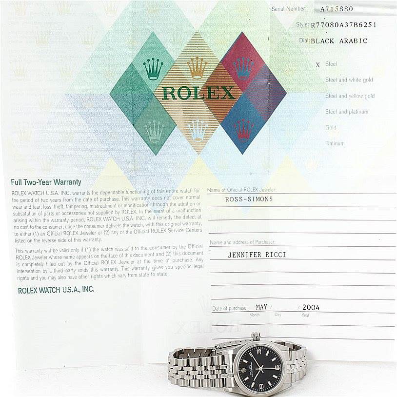 The image shows a Mid-Size Rolex watch lying flat with its bracelet extended, placed in front of warranty documents. 