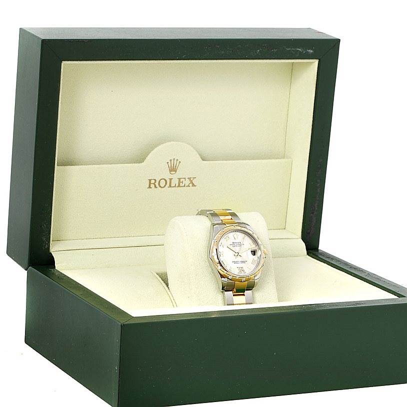 The image shows a Mid-Size Rolex watch in an open green and cream-colored box, displaying the face and part of the bracelet.