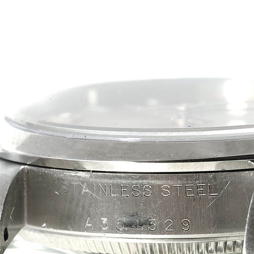 The image shows a close-up angle of the Mid-Size Rolex watch, focusing on the case side with "STAINLESS STEEL" engraving.