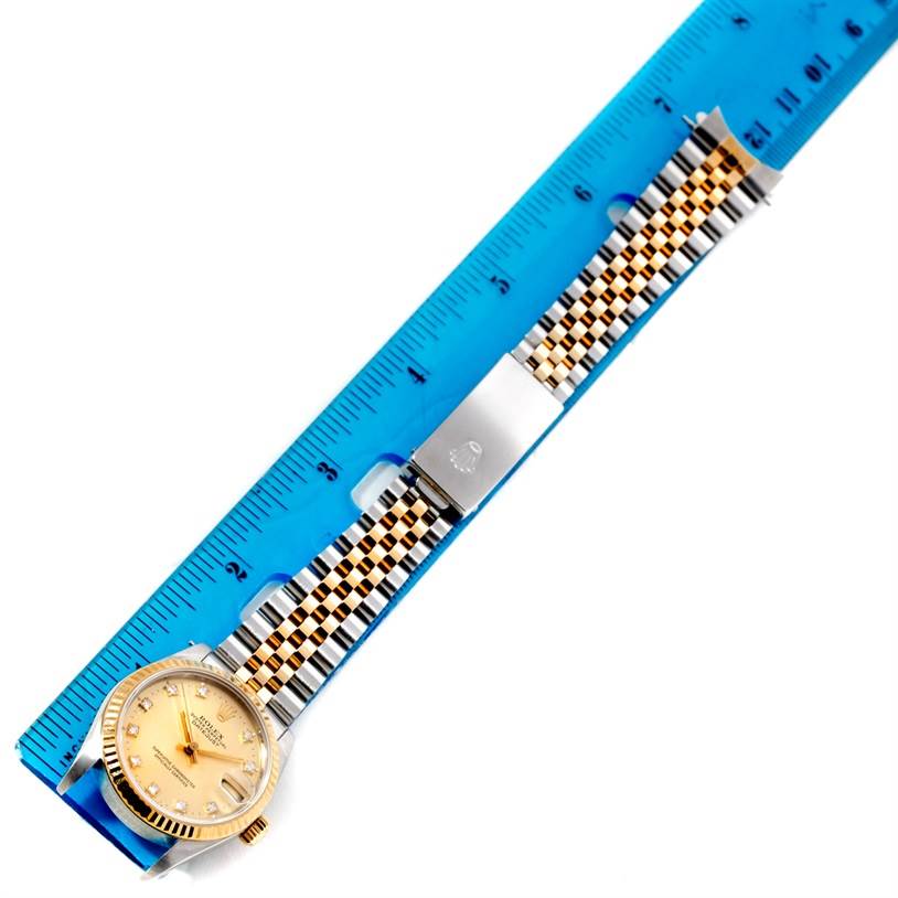 This image shows a Rolex Mid-Size 68273 Women's Stainless Steel Champagne Dial 68273 Women's Stainless Steel Champagne Dial watch laid flat next to a blue ruler, highlighting its band and face.