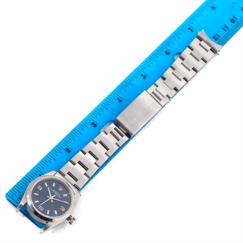 The image shows a Rolex Mid-Size 77080 Women's Stainless Steel Blue Dial 77080 Women's Stainless Steel Blue Dial model watch lying flat next to a blue ruler, displaying its face and metal bracelet.