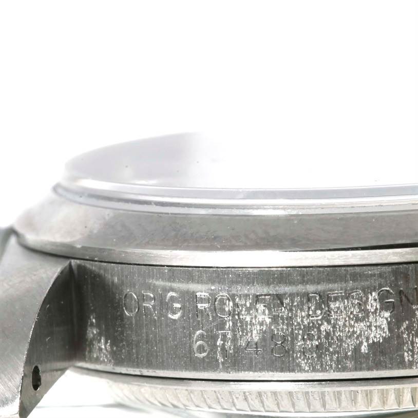 The image shows a side view of the Rolex Mid-Size 67480 Women's Stainless Steel Black Dial 67480 Women's Stainless Steel Black Dial model focusing on the casing and part of the bezel with the serial numbers engraved.