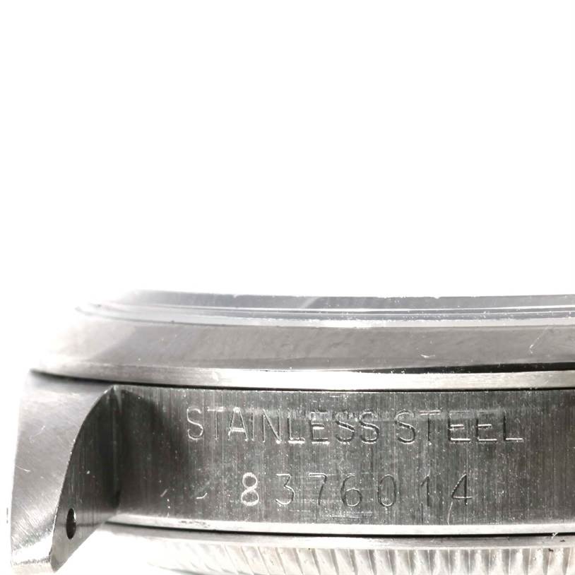 This image shows a close-up, side view of the stainless steel case back of a Mid-Size Rolex watch, displaying part of its serial number.