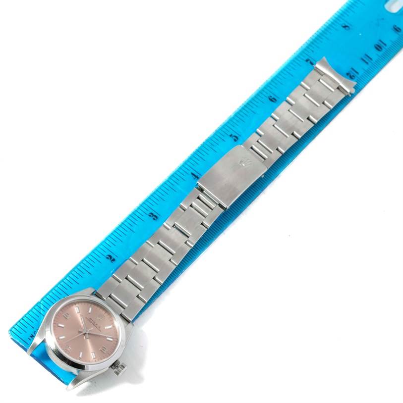 The image shows a Rolex Mid-Size 77080 Women's Stainless Steel Pink Dial 77080 Women's Stainless Steel Pink Dial model watch with a silver band, laid flat alongside a blue ruler.