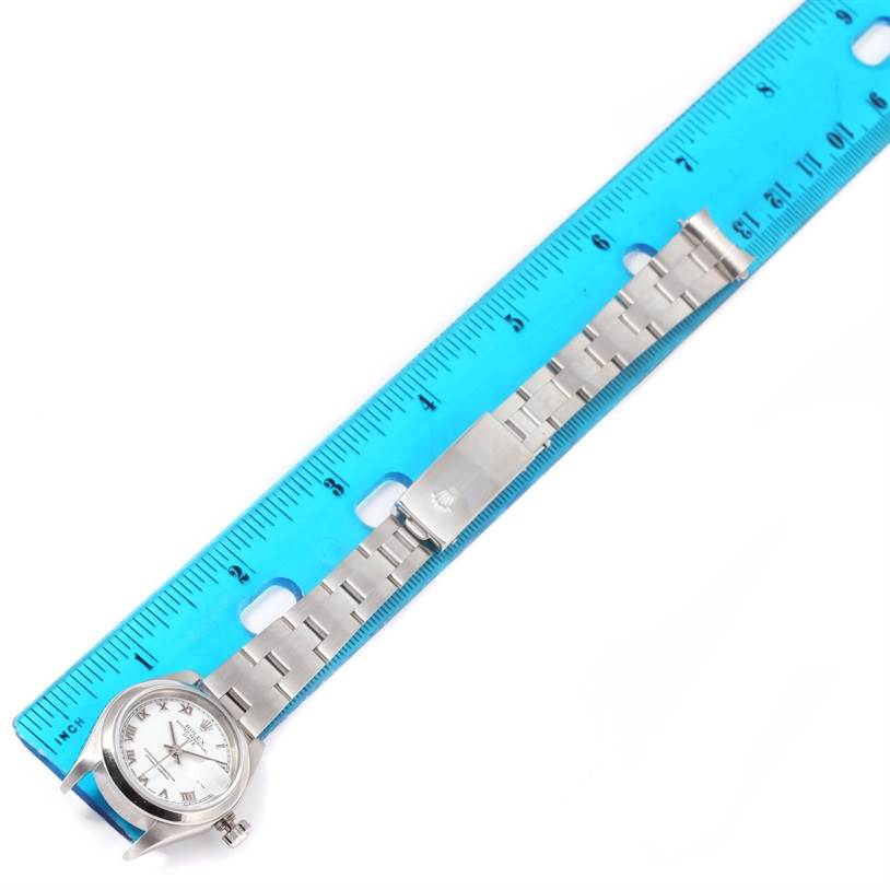 The image shows a Rolex Date 79160 Women's Stainless Steel White Dial 79160 Women's Stainless Steel White Dial model watch laid flat alongside a blue ruler, capturing the watch face, bezel, and metallic bracelet with clasp.