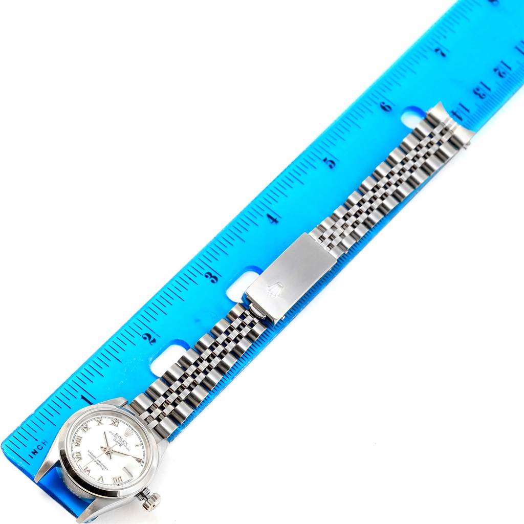 The image shows a Rolex Date 79160 Women's Stainless Steel White Dial 79160 Women's Stainless Steel White Dial watch laid flat next to a blue ruler, displaying its watch face, bracelet, and clasp.