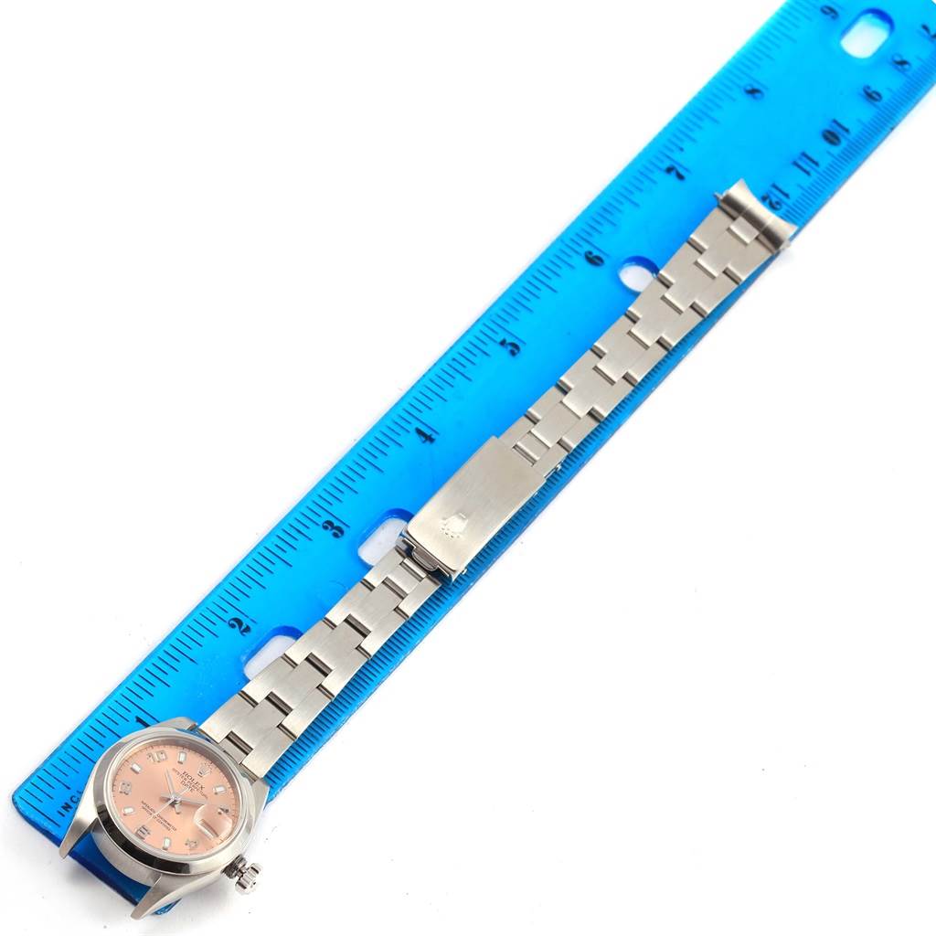 This image shows a Rolex Date 79160 Women's Stainless Steel Pink Dial 79160 Women's Stainless Steel Pink Dial model watch placed alongside a blue ruler, highlighting the watch's bracelet and clasp.