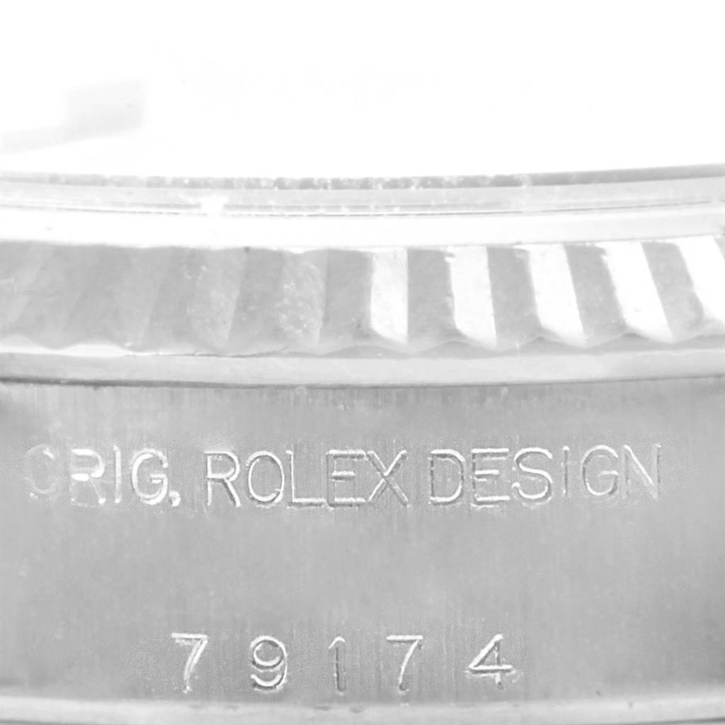 The image shows a close-up of the case side engraving and fluted bezel of a Rolex Date 79174 Women's Stainless Steel Blue Dial 79174 Women's Stainless Steel Blue Dial model watch.