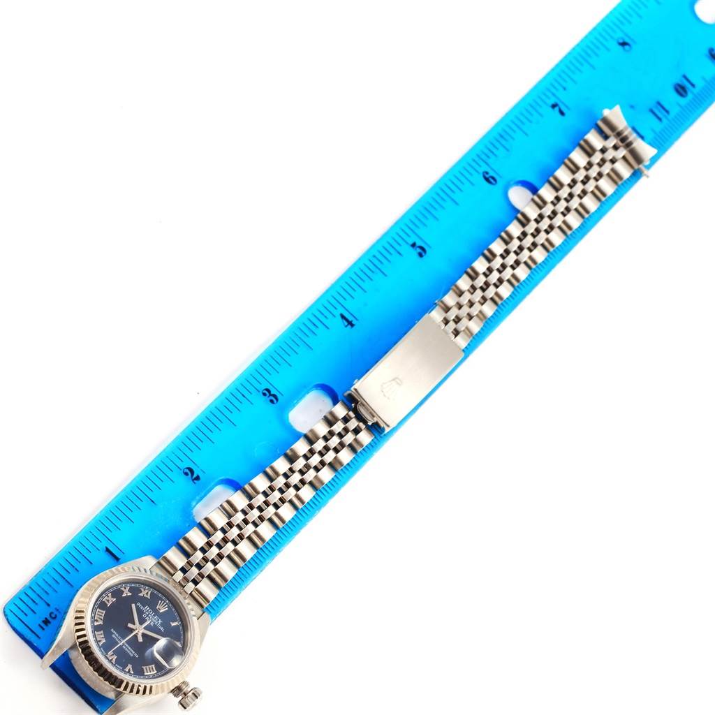 The image shows the Rolex Date 79174 Women's Stainless Steel Blue Dial 79174 Women's Stainless Steel Blue Dial model watch from the top view, alongside a blue ruler to measure its length.