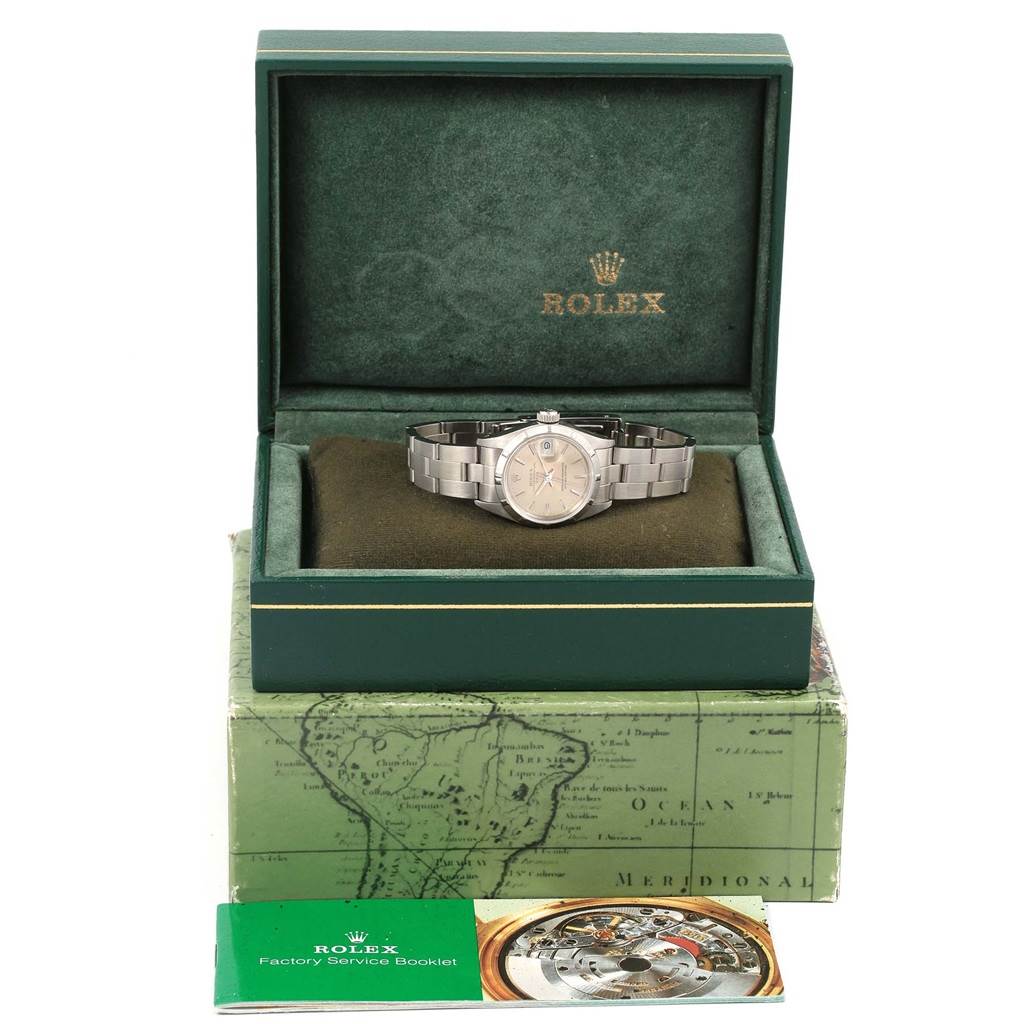 The Rolex Date 69190 Women's Stainless Steel Silver Dial 69190 Women's Stainless Steel Silver Dial watch is shown from the front in its green box with a factory service booklet beside it.