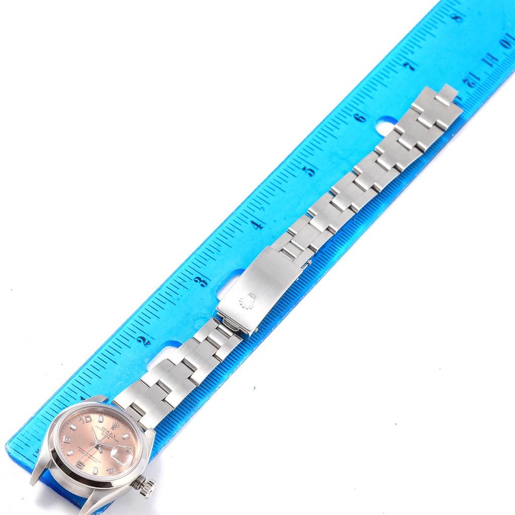 The image shows a top-down view of a Rolex Date 79160 Women's Stainless Steel Pink Dial 79160 Women's Stainless Steel Pink Dial model watch with its bracelet laid next to a ruler.