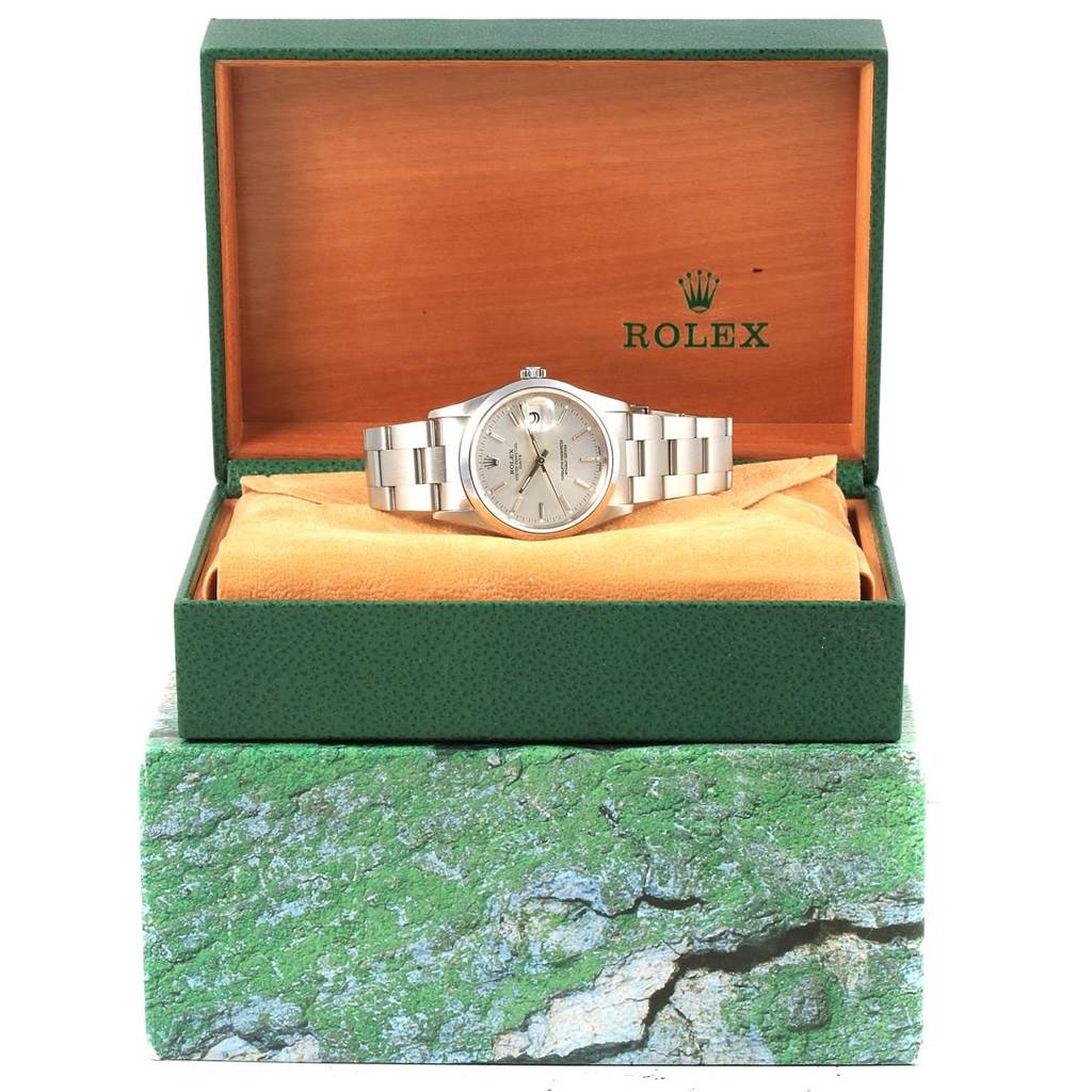 The Rolex Date 15200 Men's Stainless Steel Silver Dial 15200 Men's Stainless Steel Silver Dial watch is shown from the front, displayed inside its green and wooden case, with a visible silver bracelet.