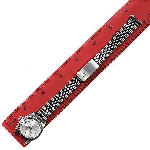 The image shows a Rolex Date 79240 Women
s Stainless Steel Silver Dial 79240 Women
s Stainless Steel Silver Dial model watch laid flat on a red ruler, displaying the face, bezel, and the full metal bracelet.