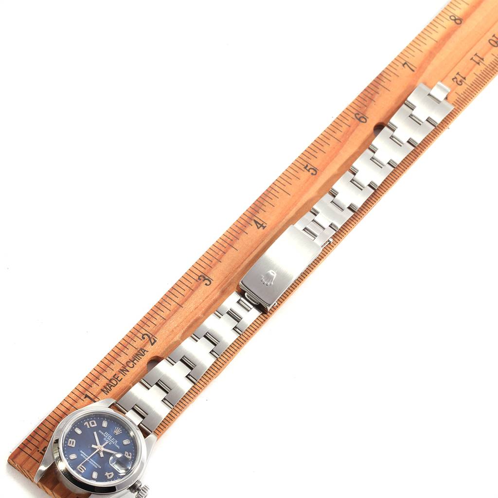 The Rolex Date 79160 Women's Stainless Steel Blue Dial 79160 Women's Stainless Steel Blue Dial watch model is shown laid flat against a ruler, displaying the face, bracelet, and clasp.