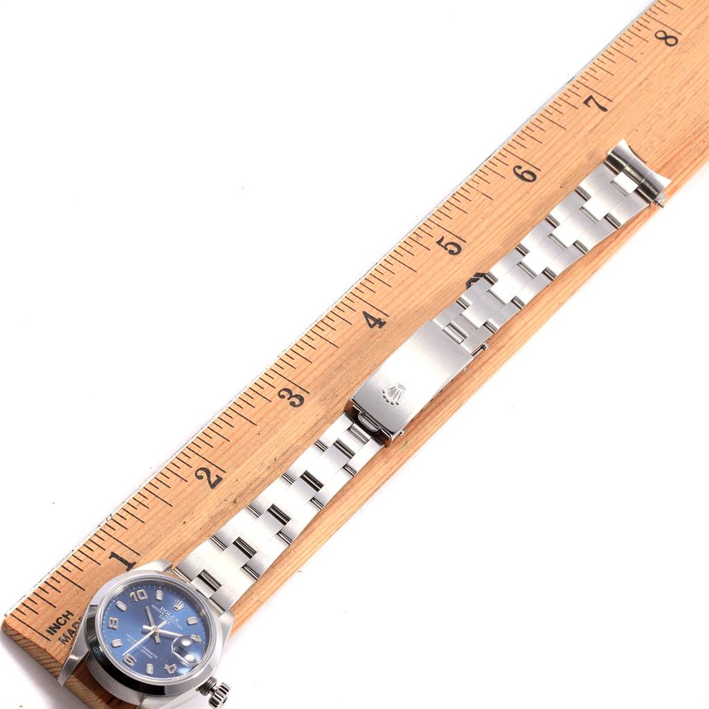 This image shows a Rolex Date 79160 Women
s Stainless Steel Blue Dial 79160 Women
s Stainless Steel Blue Dial model watch laid flat next to a ruler, displaying its face, bracelet, and clasp.