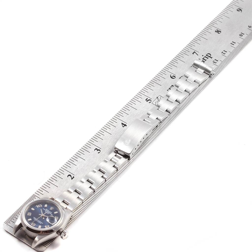 The Rolex Date 69160 Women's Stainless Steel Blue Dial 69160 Women's Stainless Steel Blue Dial watch is shown from an angled top view, with a focus on the watch face, bracelet, and clasp next to a ruler.