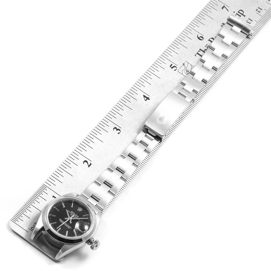 The Rolex Date 79160 Women
s Stainless Steel Black Dial 79160 Women
s Stainless Steel Black Dial watch is shown horizontally with its links and clasp laid alongside a ruler.