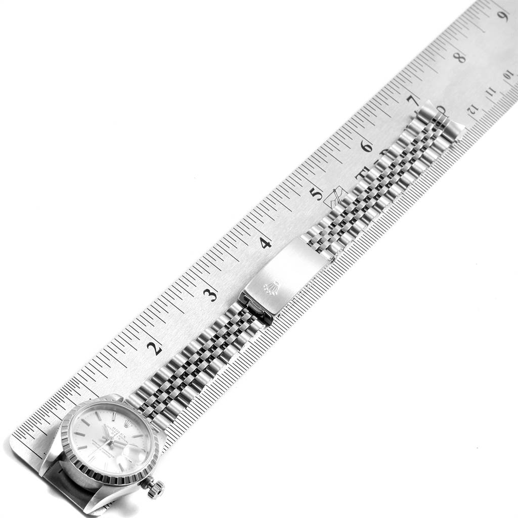 The image shows a top-down view of a Rolex Date 69240 Women's Stainless Steel Silver Dial 69240 Women's Stainless Steel Silver Dial model watch, including part of the dial, bracelet, and clasp placed on a ruler.