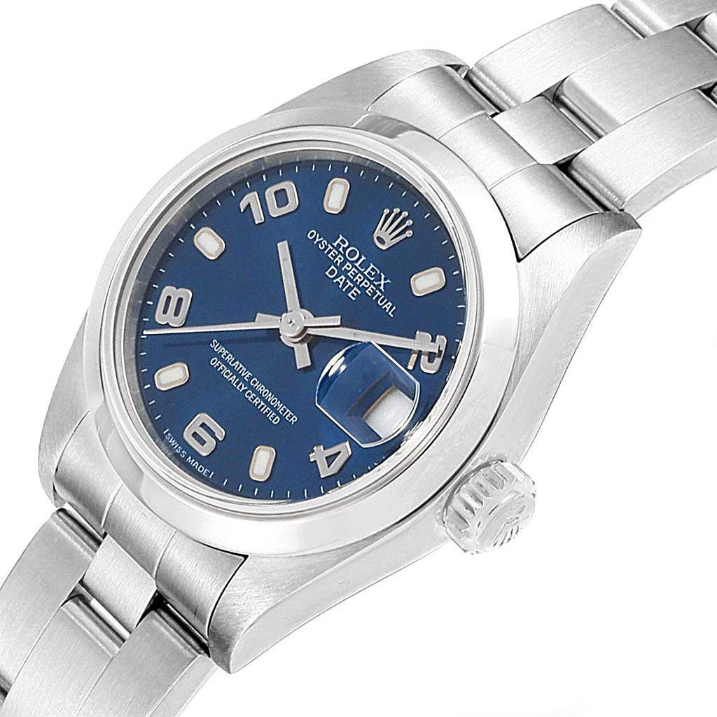 The image shows a close-up angled view of a Rolex Oyster Perpetual Date, highlighting the blue dial, crown, and part of the bracelet.