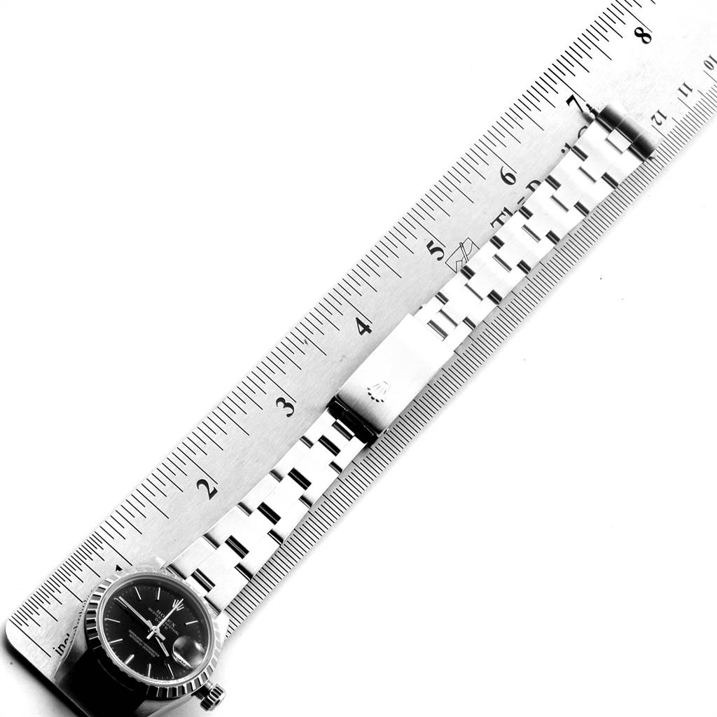 The image shows a flat-lay view of a Rolex Date 79240 Women's Stainless Steel Black Dial 79240 Women's Stainless Steel Black Dial model showcasing the watch dial, bracelet, and clasp alongside a ruler for scale.