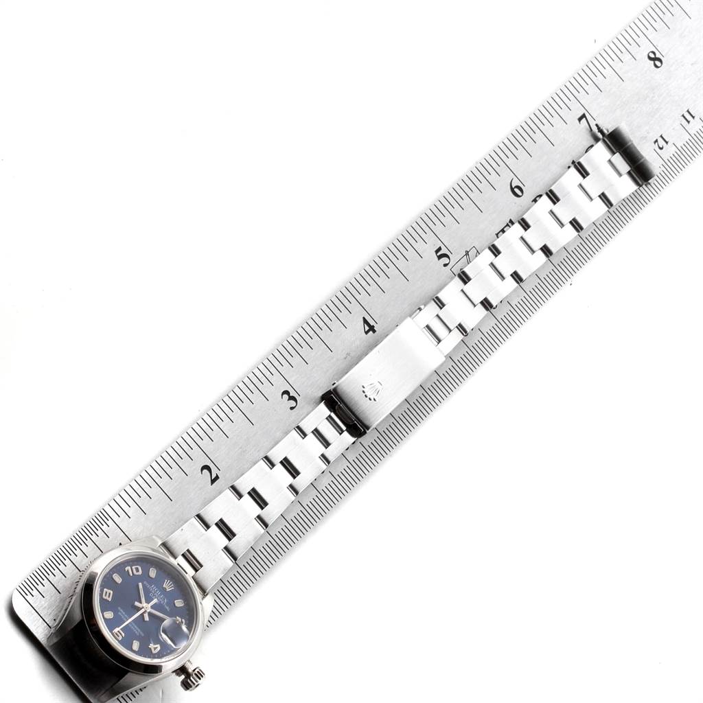 The image shows a Rolex Date 79160 Women's Stainless Steel Blue Dial 79160 Women's Stainless Steel Blue Dial model watch laid against a ruler, showcasing the watch face and metal bracelet.