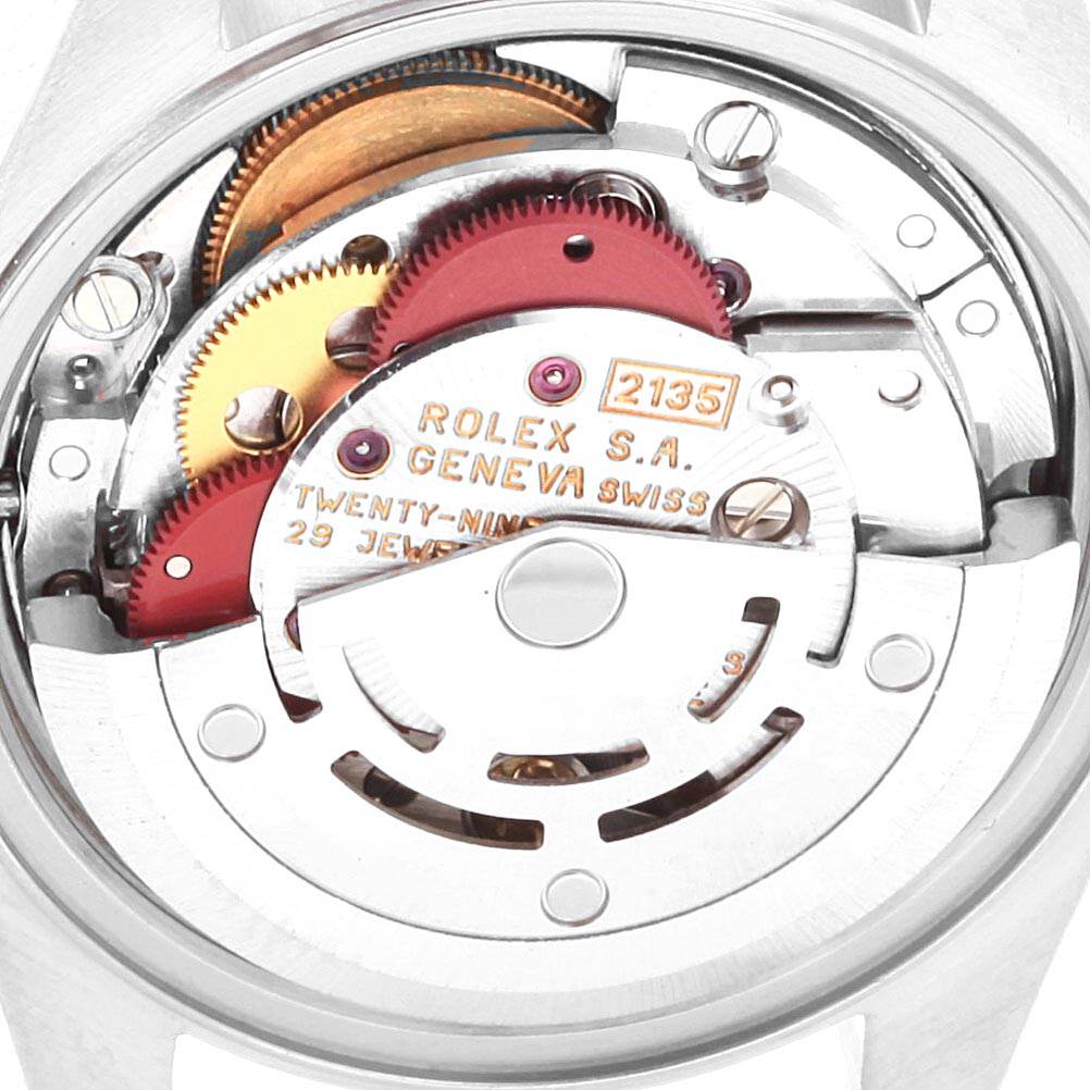 The image shows the internal mechanism of a Rolex Date 69160 Women
s Stainless Steel Silver Dial 69160 Women
s Stainless Steel Silver Dial model watch from a top-down angle, displaying gears and inscriptions.